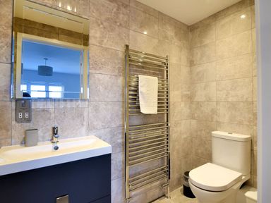 A bathroom with a sink and mirror towel rack with towel and toilet at Shire View in Lyme Regis