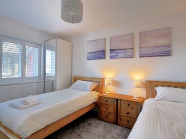 A bedroom with two single beds and a wooden nightstand with lamps at Shire View in Lyme Regis