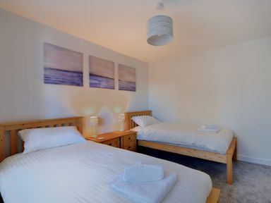 A bedroom with two single beds bedside table and three paintings on the wall at Shire View in Lyme Regis