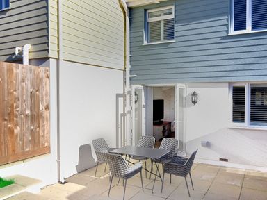 An outdoor patio area with a table and six chairs outside a house with blue and white siding at Shire View in Lyme Regis