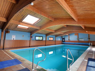 An indoor swimming pool with metal handrails and skylights at 10 Pinewood Retreat in Pinewood