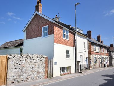 A row of houses with a stone wall and a street lamp on a street at Bay View in Lyme Regis