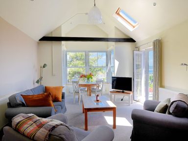 A living room with sofas a coffee table dining table and TV at Bay View in Lyme Regis