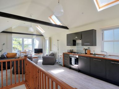 An open plan kitchen and living area with black cabinets wooden countertops sofas and a dining table at Bay View in Lyme Regis