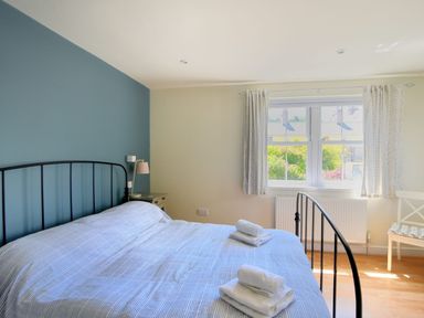 A bedroom with a double bed and folded towels on it next to a window with curtains at Bay View in Lyme Regis