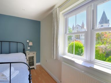 A bedroom with a bed a bedside table and window overlooking a church at Bay View in Lyme Regis