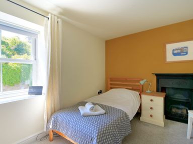 A bedroom with a single bed bedside table and lamp next to a fireplace at Bay View in Lyme Regis