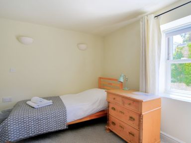 A bedroom with a single bed and a wooden dresser next to a window at Bay View Lyme Regis