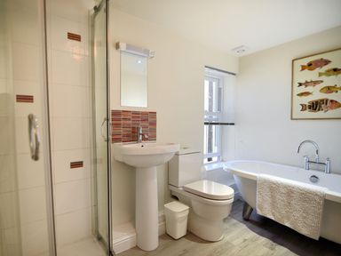 A bathroom with a shower cubicle sink toilet bathtub and a window at Bay View Lyme Regis