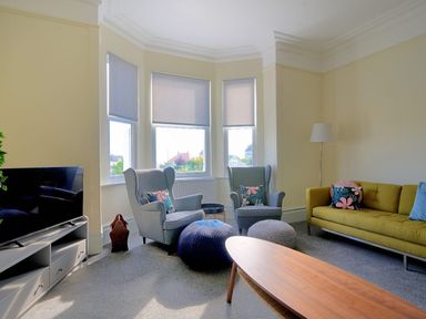 A living room with two armchairs a green sofa a wooden coffee table and a television at 7 Seafield Road in Seaton