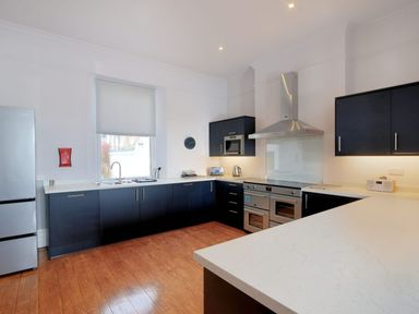 A kitchen with dark cabinets white countertops stainless steel appliances and wooden floor at 7 Seafield Road in Seaton