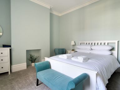 A bedroom with a white bed and teal bench at 7 Seafield Road in Seaton
