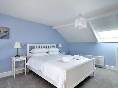 A bedroom with a white bed and bedside tables with lamps under a skylight window at 7 Seafield Road in Seaton