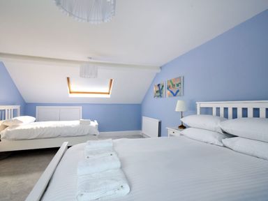 A bedroom with two white beds blue walls a skylight window and folded towels on a bed at 7 Seafield Road in Seaton