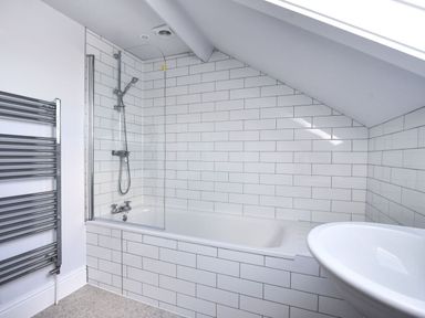 A bathroom with a bathtub shower combination towel rack and sink at 7 Seafield Road in Seaton