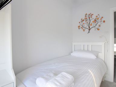 A bedroom with a single bed white bedding folded towels and a decorative wall art at 7 Seafield Road in Seaton