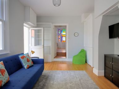 A living room with a blue sofa and green bean bag near a doorway with stained glass at 7 Seafield Road in Seaton