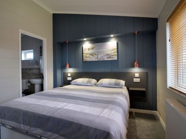 A bedroom with a bed and bedside shelves next to a window at Hazelwood 4 @ Pinewood Retreat in Pinewood