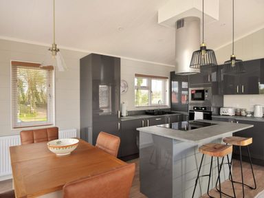 A kitchen with a dining table and chairs a kitchen island with two stools and hanging lights at Hazelwood 4 Pinewood Retreat in Pinewood