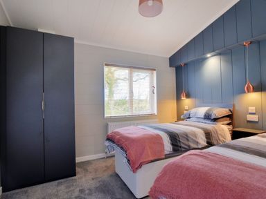A bedroom with two single beds a black wardrobe and a window at Hazelwood 4 @ Pinewood Retreat in Pinewood