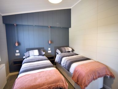 A bedroom with two single beds with striped bedding and pink throws at Hazelwood 4 @ Pinewood Retreat in Pinewood