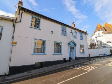 A white building with blue window frames and a blue door on a street with a road marking at Old Monmouth Lyme Regis