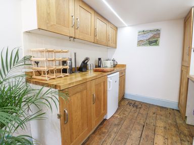 A kitchen with wooden cabinets wooden countertop a small refrigerator and kitchen utensils at Old Monmouth in Lyme Regis