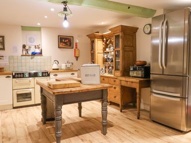 A kitchen with wooden cabinets a central island and stainless steel refrigerator at Old Monmouth Lyme Regis