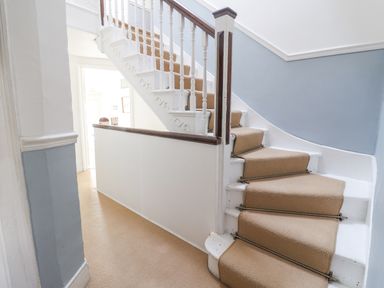 A staircase with beige carpet and white railings in a hallway at Old Monmouth Lyme Regis