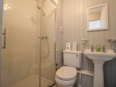 A bathroom with a glass shower enclosure a toilet and a pedestal sink with a mirror above at Old Monmouth in Lyme Regis