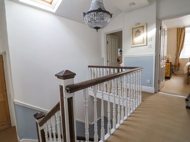 A hallway with a wooden and white banister and chandelier at Old Monmouth in Lyme Regis
