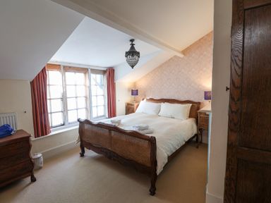 A bedroom with a wooden bed white bedding bedside tables with lamps and a large window at Old Monmouth in Lyme Regis