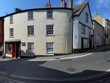 A street view with old buildings and a shop with red framing at Driftwood in Lyme Regis