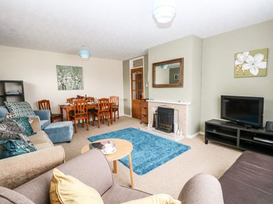 A living room with sofas a wooden dining table a TV on a stand and a fireplace at Sunny Haven in Preston