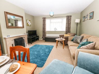 A living room with sofas a television on a stand and a blue rug at Sunny Haven in Preston