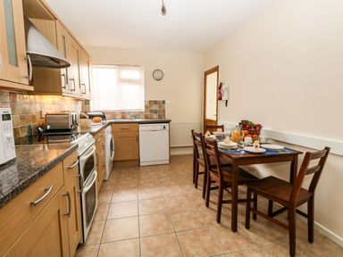 A kitchen with wooden cabinets and a dining table set for four at Sunny Haven in Preston
