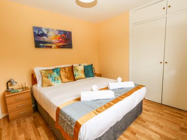A bedroom with a double bed pillows bedside tables lamps and a wardrobe at Sunny Haven in Preston