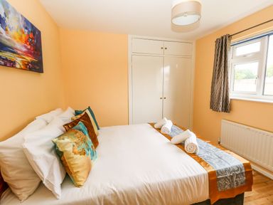 A bedroom with a bed with pillows and rolled towels a window with curtains and a built in wardrobe at Sunny Haven in Preston