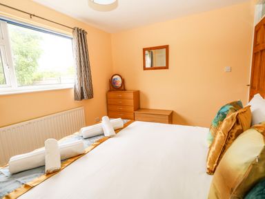 A bedroom with a bed pillows rolled towels window chest of drawers mirror and curtain at Sunny Haven in Preston