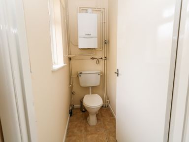 A small bathroom with a toilet a window and a boiler on the wall at Sunny Haven in Preston