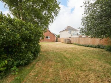 A backyard with grass lawn trees shrubbery and two houses in the background at Sunny Haven in Preston