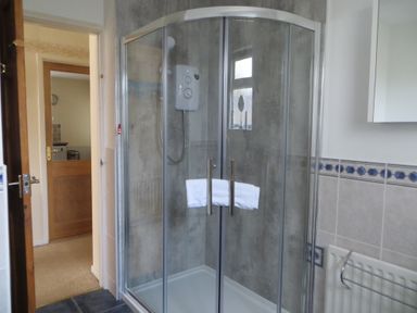 A bathroom with a shower enclosure a white towel a radiator and partial view of a mirror cabinet at Sunny Haven in Preston