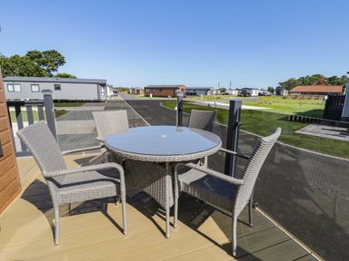 An outdoor patio with a round glass table and four wicker chairs at Away Daze Carnaby near Bridlington