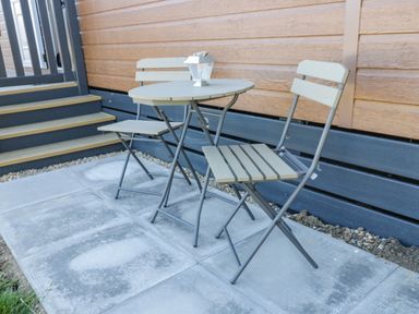 An outdoor seating area with a small round table and two folding chairs on a paved patio at Away Daze in Carnaby near Bridlington