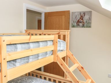 A bedroom with a wooden bunk bed and a painting of a rabbit on the wall at Sawtons Cottage 2 in Dawlish