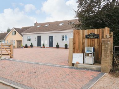 A paved driveway with two doors on a modern building and a wooden sign for Sawtons View Nursery at Sawtons Cottage 2 in Dawlish
