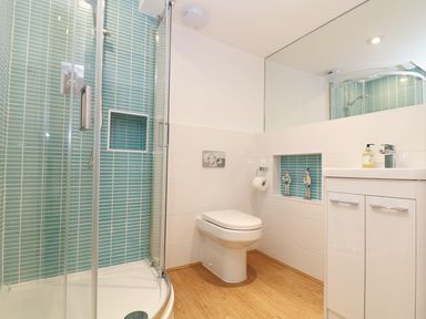 A bathroom with a corner shower enclosure a toilet and a sink with a cabinet and mirror at Port View in Falmouth