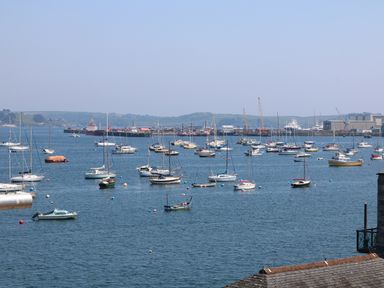 A harbor with many boats anchored in the water and industrial buildings in the background at Port View in Falmouth