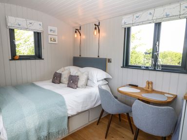 A bedroom with a bed and two gray chairs at Cwt Y Rhos in Valley