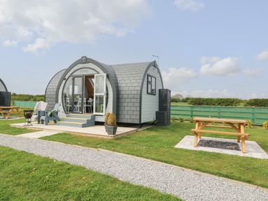 A small modern pod with outdoor chairs and a picnic table on a grassy area at Primrose in Seaton near Hornsea